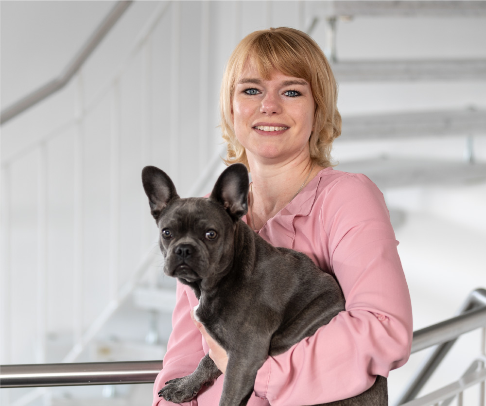 Porträt von Caroline Matt mit Hund, zuständig für das Rechnungswesen bei Ingenieurbüro Stefan Matt, vor neutralem Hintergrund.
